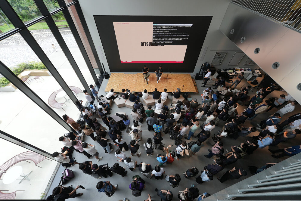 A full auditorium at a Y Combinator event with subtitles on the main screen